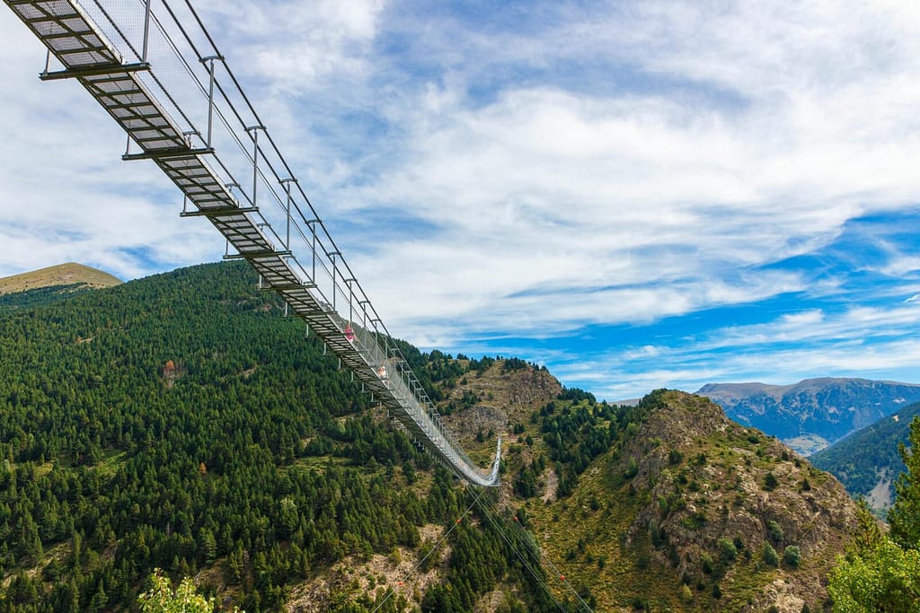 Breathtaking suspension bridge spanning lush green valley, perfect for adventurous travel seekers.